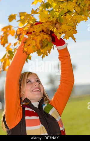 Smiling young girl picking arbre automne feuilles sèches Banque D'Images