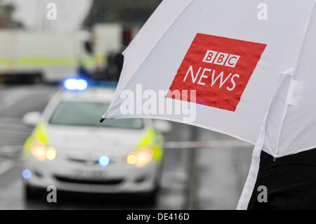 Ballyclare, Irlande du Nord. 11 septembre 2013 - Journaliste détient un parapluie de BBC News tout en observant l'activité de l'armée et la police Crédit : Stephen Barnes/Alamy Live News Banque D'Images