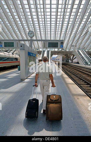 Autorisation modèle senior man des personne qui marche avec valise bagages sur la plate-forme de la gare de l'Union européenne Belgique Liège bâtiment moderne en verre Banque D'Images