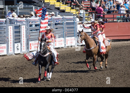 Cowgirl flagbearers galoper à cheval avec American stars and stripes drapeaux, rodéo d'Ellensburg cérémonie d ouverture, WA, USA Banque D'Images