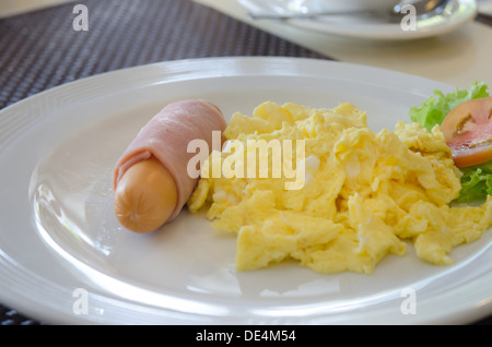 Oeufs brouillés , jambon et saucisses servis avec légumes frais on white plate Banque D'Images