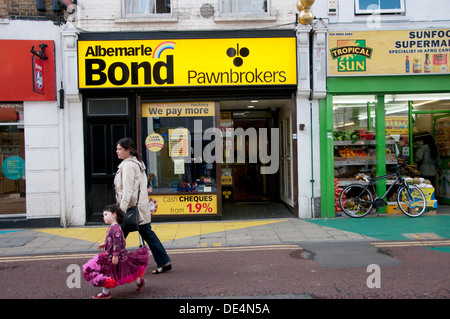 Hackney. Chemin étroit. Mère et fille en passant devant un magasin de jouet Banque D'Images
