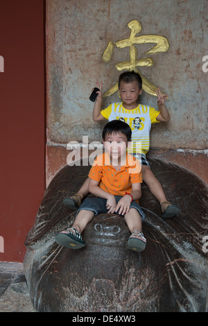 Les Tombeaux des Ming, Nanjing, Chine. Les enfants jouant sur la tortue maintenant l'Empereur Kangxi stèle à la tablette Hall. Banque D'Images