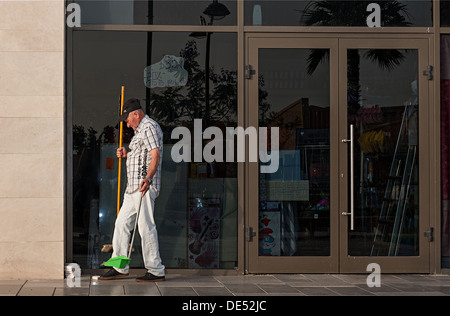 Un travailleur nettoyage nettoyer et balayer une place du marché à Mahebourg, Mauritius Banque D'Images