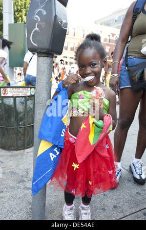 2012 West Indian/Caraïbes Kiddies parade, Crown Heights. Young Girl eating ice porte drapeaux de la Grenade et Sainte Lucie. Banque D'Images