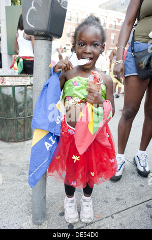 2012 West Indian/Caraïbes Kiddies parade, Crown Heights. Young Girl eating ice porte drapeaux de la Grenade et Sainte Lucie Banque D'Images