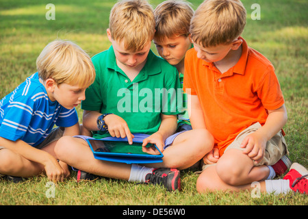 Groupe d'enfants sur l'herbe using tablet computer Banque D'Images