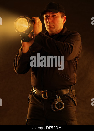 Policier avec des recherches dans le secteur de la flamme allumée Banque D'Images