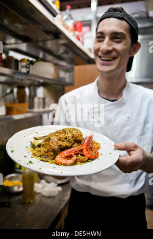 Un chef cuisinier prépare une pâte noir et plat de langoustines dans une cuisine de restaurant. Banque D'Images