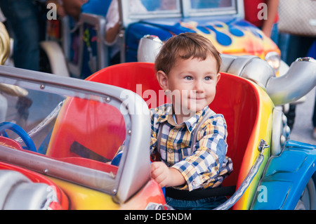 Little Boy riding a car in amusement park Banque D'Images