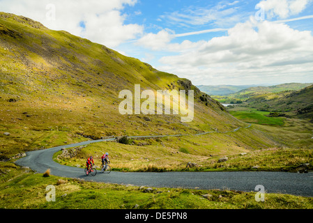 Les cyclistes gravir les pentes Wrynose Pass dans le Lake District avec peu derrière Langdale Banque D'Images