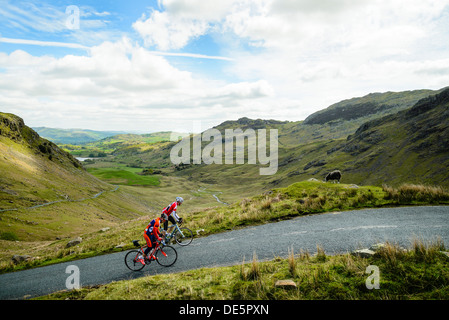 Les cyclistes gravir les pentes Wrynose Pass dans le Lake District avec peu derrière Langdale Banque D'Images