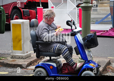 Eating Chips sur scooter de mobilité Banque D'Images