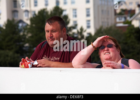 L'excès de couple par mur, man eating paquet de chips, à Bournemouth en Septembre Banque D'Images