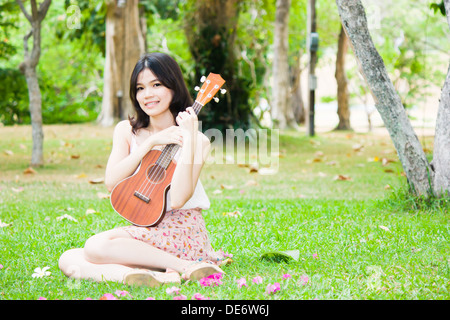 Asian girl avec ukulele guitare en plein air jardin Banque D'Images