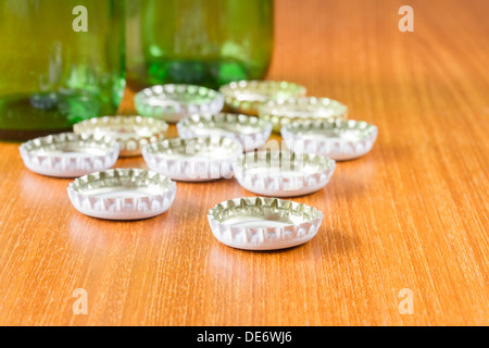 Les bouteilles de bière avec white caps sur une table en bois Banque D'Images