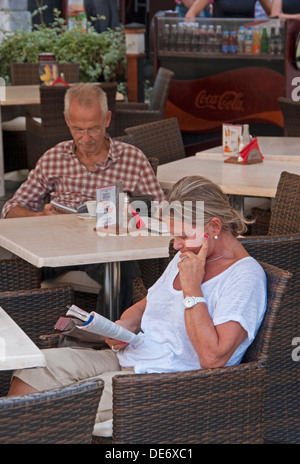 Le lecteur à la place du marché principal de Cracovie à outdoor tables de restaurant. Banque D'Images