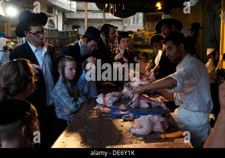 Jérusalem, Israël. Sept 12, 2013. Un vendeur de poulets coupe arabe après le rituel de Yom Kipur Kapparot veille à Mea Shearim quartier dans l'approche de Yom Kippour le 11 septembre 2013. Dans la pratique religieuse juive de Kapparot, un coq devient littéralement un navire sacré et religieux et pivote autour de la tête puis sacrifiés sur l'après-midi avant Yom Kippour, le Jour des Expiations. Credit : Eddie Gerald/Alamy Live News Banque D'Images