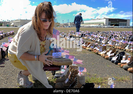 Shannon Cleary, soeur de la 1ère Armée Le lieutenant Michael J. Cleary, qui a perdu la vie au cours de l'opération Iraqi Freedom affiche son frère lors d'une initialisation de la memorial 6 000 bottes avec les noms et photos des victimes de l'Irak et des guerres afghanes sur l'affichage sur l'Île Ford Joint Base Pearl 11 septembre 2013 Harbor-Hickam, à Pearl Harbor, Hawaii. Banque D'Images