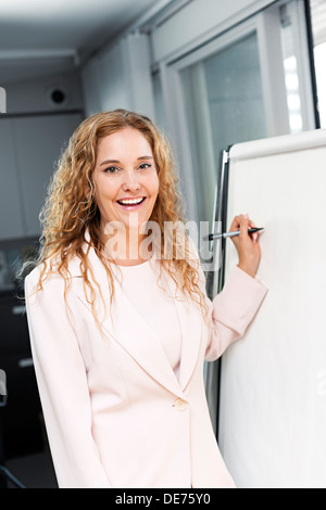 Smiling businesswoman écrit sur le tableau in office Banque D'Images