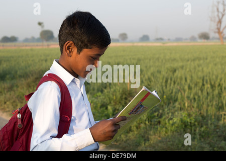 L'Inde, Uttar Pradesh, Agra, jeune garçon en uniforme d'à la recherche de livre de texte Banque D'Images