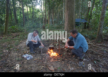 Deux voyageurs la cuisson sur un feu ouvert dans la jungle vierge de Surama, Guyana, en Amérique du Sud Banque D'Images