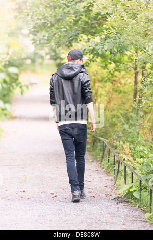 Jeune homme marche sur sentier dans un parc Banque D'Images