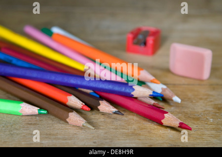 Crayons de couleur avec taille-crayon et de caoutchouc sur le vieux bureau en bois haut Banque D'Images