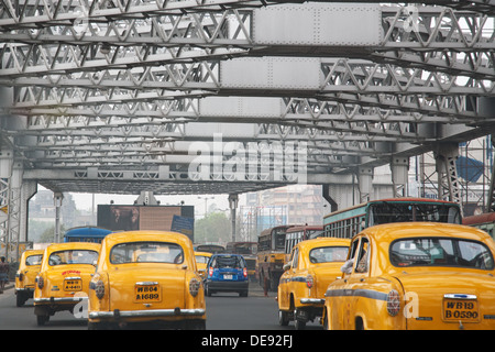 L'Ambassadeur jaune des taxis (cabines) crossing Howrah Bridge à Kokata (Calcutta), Inde Banque D'Images