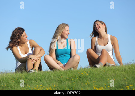 Groupe de trois adolescentes rire et parler dans l'herbe avec le ciel en arrière-plan Banque D'Images