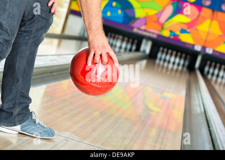 Jeune homme de bowling s'amuser, les lecteurs de l'homme tenant une boule de bowling en face de la ten pin alley Banque D'Images