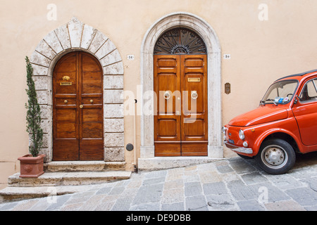 Une Fiat 500 rouge garée à côté de deux portes renaissance à Montepulciano, Toscane, Italie. Banque D'Images