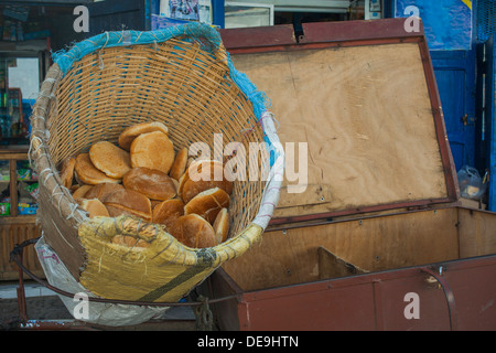 Vendeur de pain pita avec du pain en gros panier dans la rue de Rabat, Maroc Banque D'Images