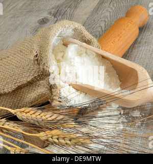 Table en bois avec un sac de farine et une cuillère à oreilles Banque D'Images
