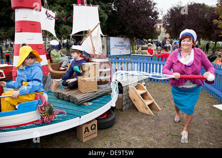 Great Yarmouth, au Royaume-Uni. 14e Août, 2013. Parents et grands-parents l'alimentation Seachange Carrousel, un carrousel écologique à la main à partir de matériaux recyclables par groupe d'arts de Yarmouth le Carrousel collectif. L'une des nombreuses expositions imaginatives au dehors là - Great Yarmouth's Annual International Festival de cirque et arts de rue : Adrian Crédit Buck/Alamy Live News Banque D'Images