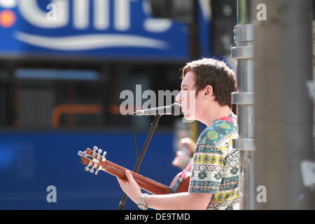 Un jeune homme musicien ambulant chante et joue de la guitare acoustique à la foule dans le centre-ville de Glasgow, Écosse, Royaume-Uni Banque D'Images