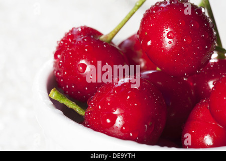 Les cerises dans un bol blanc avec des gouttes d'eau pétillante Banque D'Images