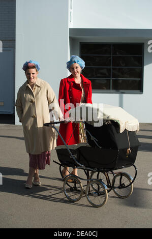 Chichester, West Sussex, UK. 14e Août, 2013. Goodwood Revival. Le circuit de course de Goodwood, West Sussex - Samedi 14 septembre. Deux dames habillés en habits d'époque y compris avoir leurs cheveux en rouleaux la pose avec un landau Crédit : MeonStock/Alamy Live News Banque D'Images