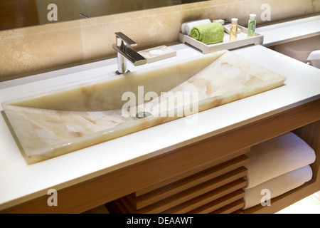 Lavabo en marbre moderne dans un hôtel Salle de bains dans un meuble en bois avec des articles de toilette et des serviettes Banque D'Images