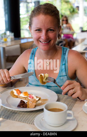 Belle Dame donnant un sourire à pleines dents tout en ayant des crêpes avec son café Banque D'Images