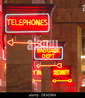 Une enseigne au néon rouge indique le chemin vers le dépôt des bagages, téléphones, et la sécurité dans la gare Banque D'Images