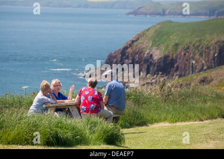 L'île de Caldey groupe de quatre amis 50d'âge moyen s'asseoir autour de la table discutant et derrière la mer, Pembrokeshire Wales UK Banque D'Images