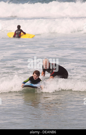 Sennen Cove homme enfant enseignement à surfer à Cornwall UK Banque D'Images