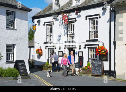 Les gens en passant devant le lion rouge à Hawkshead, Parc National de Lake District, Cumbria, Angleterre, Royaume-Uni Banque D'Images