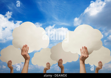 Plusieurs mains holding cut out paper nuages contre un ciel bleu avec des nuages Banque D'Images