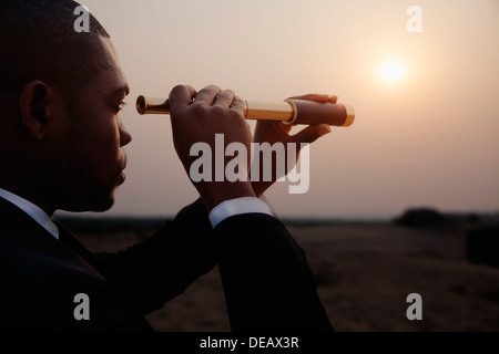 Young businessman looking through telescope au milieu du désert Banque D'Images