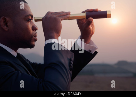 Young businessman looking through telescope au milieu du désert Banque D'Images