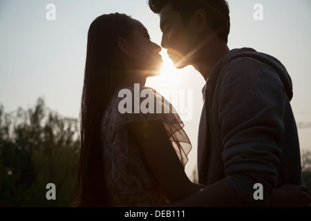 Silhouette de jeune couple très proches les unes des autres, Sunbeam et lens flare Banque D'Images