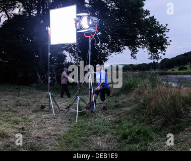 Un électricien de petites étincelles avec une grande lumière projecteur HDMI Arri équilibré sur un tournage fiction TV shoot, UK Banque D'Images