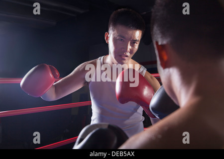 Au cours de l'épaule de deux boxeurs masculins combats dans le ring de boxe à Pékin, Chine Banque D'Images